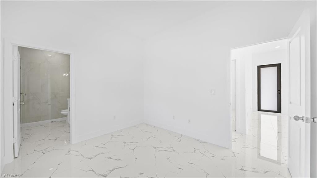 Spare room featuring light marble finish flooring and baseboards