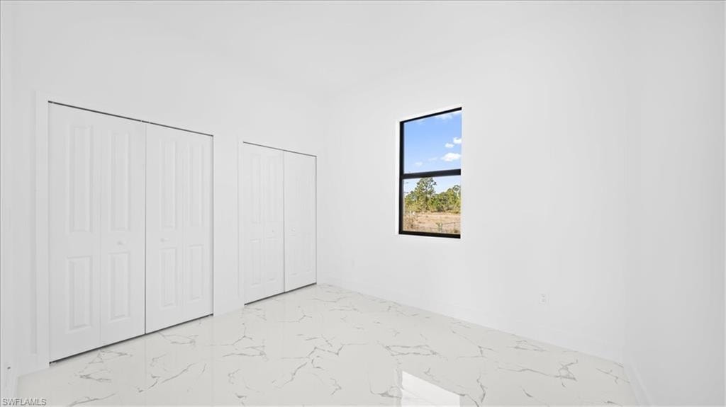Unfurnished bedroom featuring two closets and light marble finish floors
