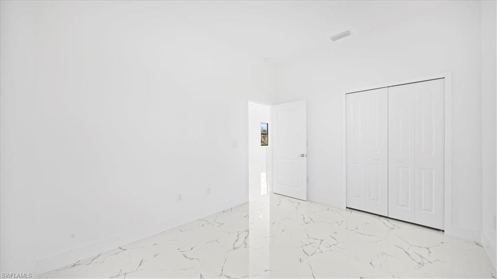 Unfurnished bedroom featuring a closet and light marble finish floors