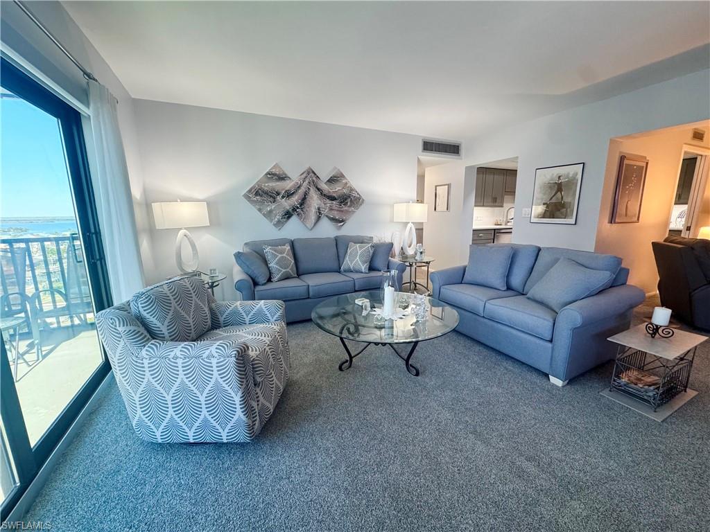 View of carpeted living area with screened balcony with views to the Gulf and the Bay