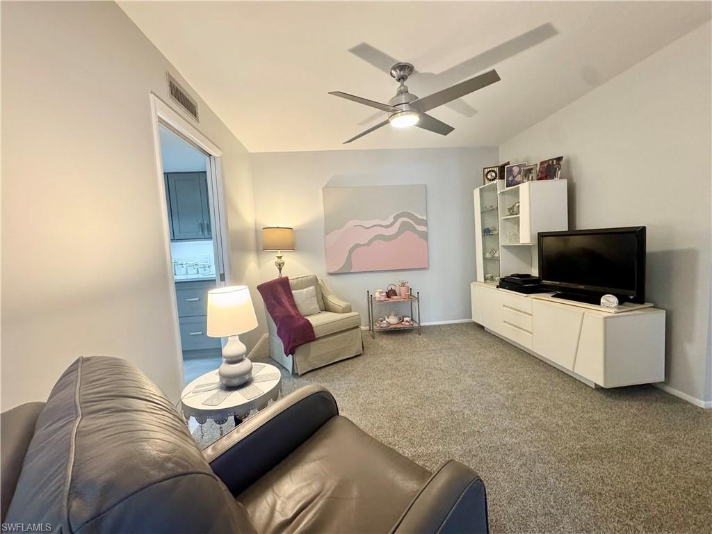 Den with carpet floors, a ceiling fan, and vaulted ceiling