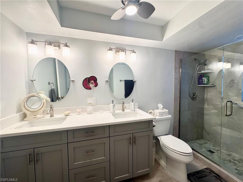 Full bath with double vanity, a shower stall, and a ceiling fan