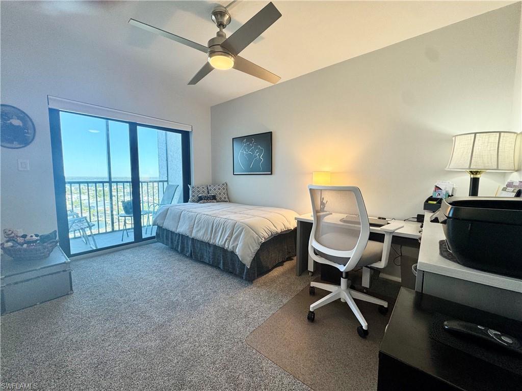 Carpeted bedroom with a desk, access to a balcony that overlooks the boat dock and Bay, and ceiling fan