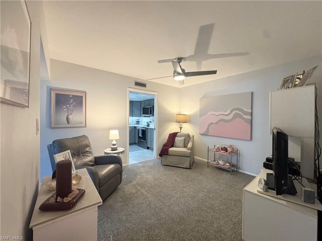 Carpeted Den featuring ceiling fan
