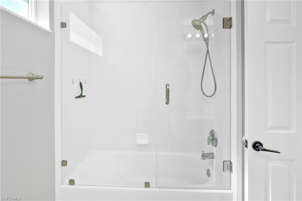 Bathroom with bath / shower combo with glass door