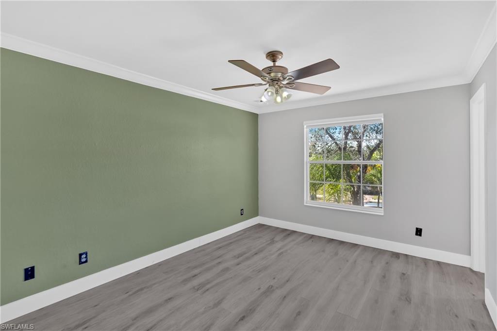 Spare room with ornamental molding, wood finished floors, and a ceiling fan
