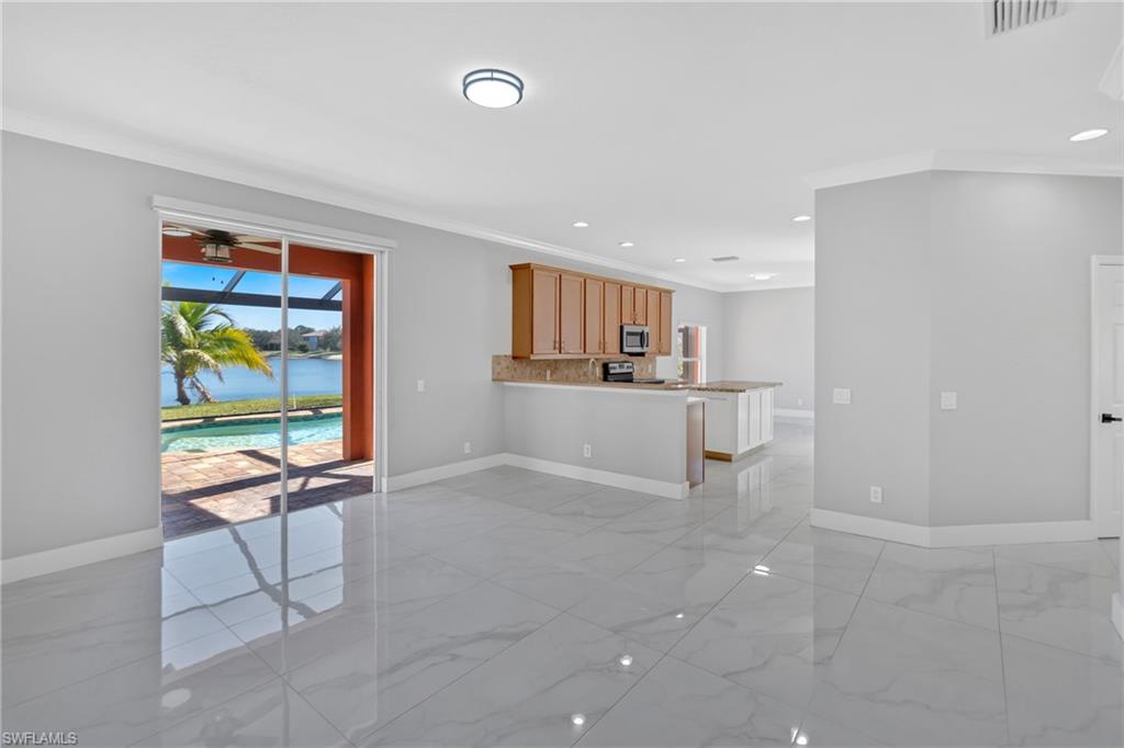 Unfurnished living room featuring crown molding, a water view, ceiling fan, recessed lighting, and light marble finish floors