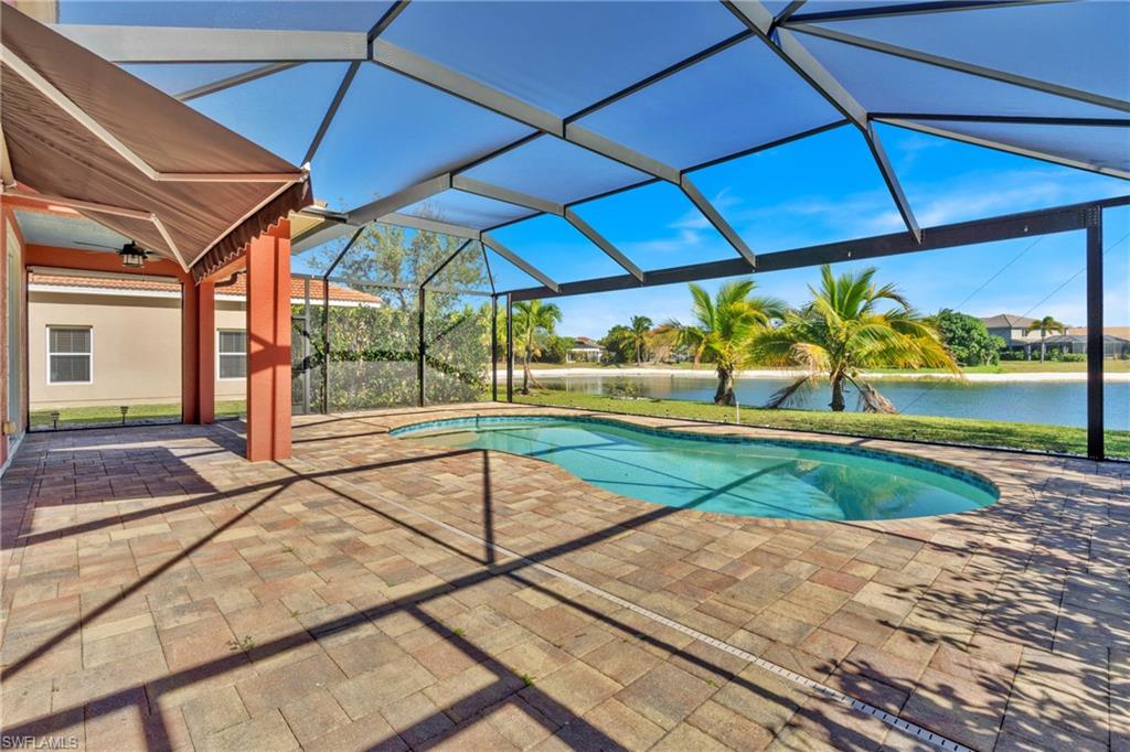 Outdoor pool featuring a patio, glass enclosure, a sunroom, and a water view