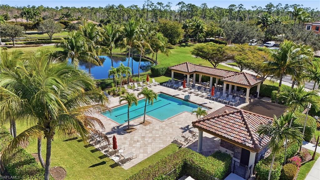 Community pool with a patio, view of scattered trees, a water view, and a lawn