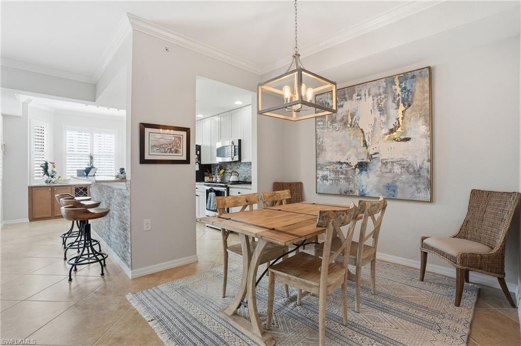 Dining room featuring light tile patterned floors, crown molding, and a chandelier