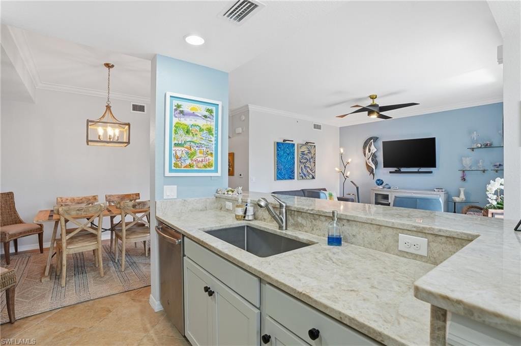 Kitchen featuring pendant lighting, light stone counters, crown molding, ceiling fan, and stainless steel dishwasher