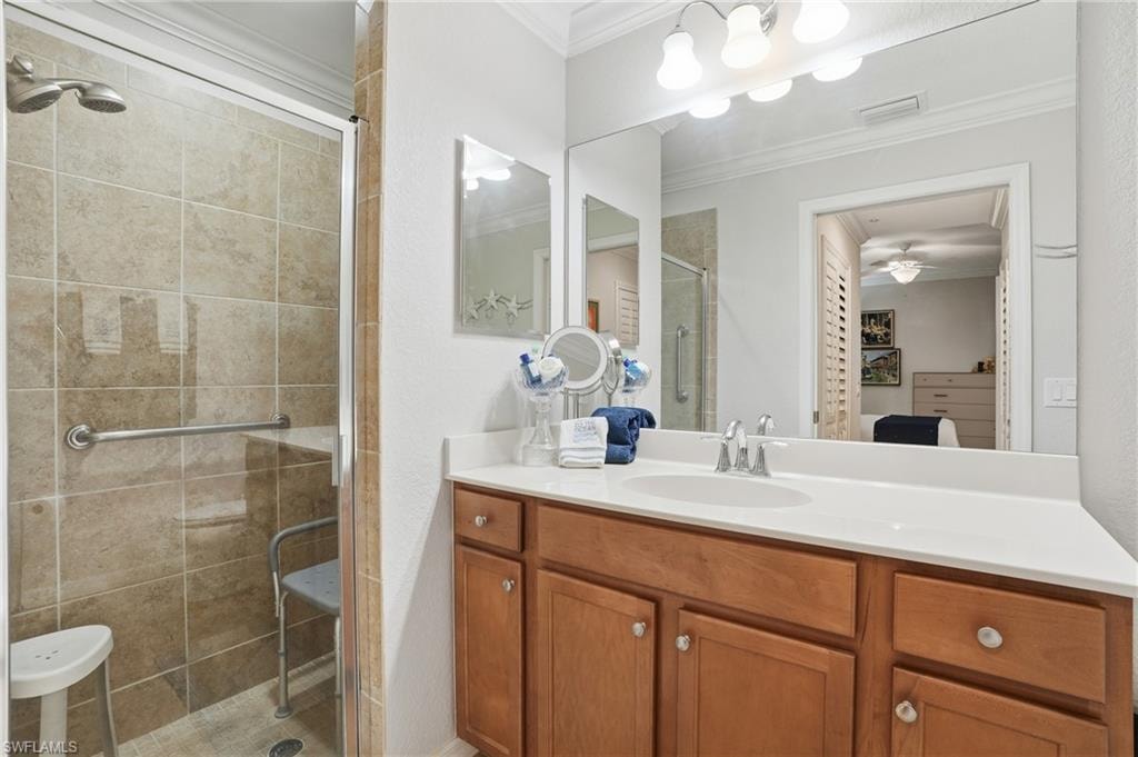 Bathroom with a stall shower, vanity, crown molding, ensuite bath, and ceiling fan