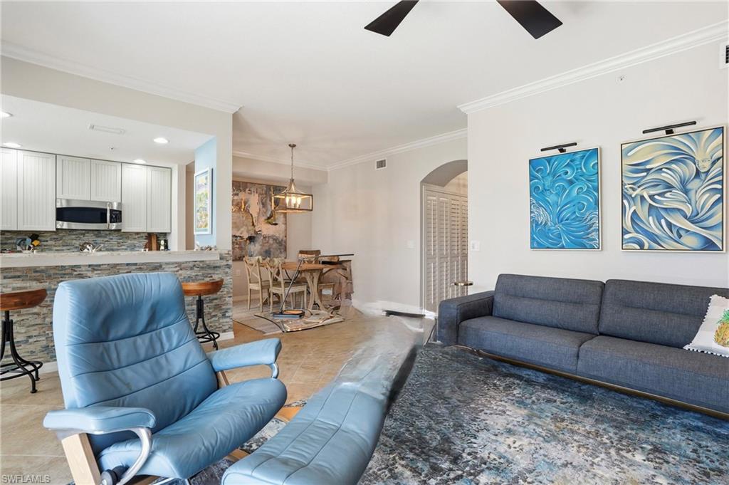 Living area featuring tile flooring, crown molding, and a ceiling fan