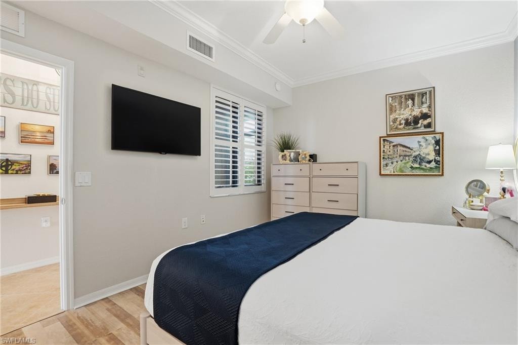 Bedroom with crown molding, wood finished floors, and a ceiling fan