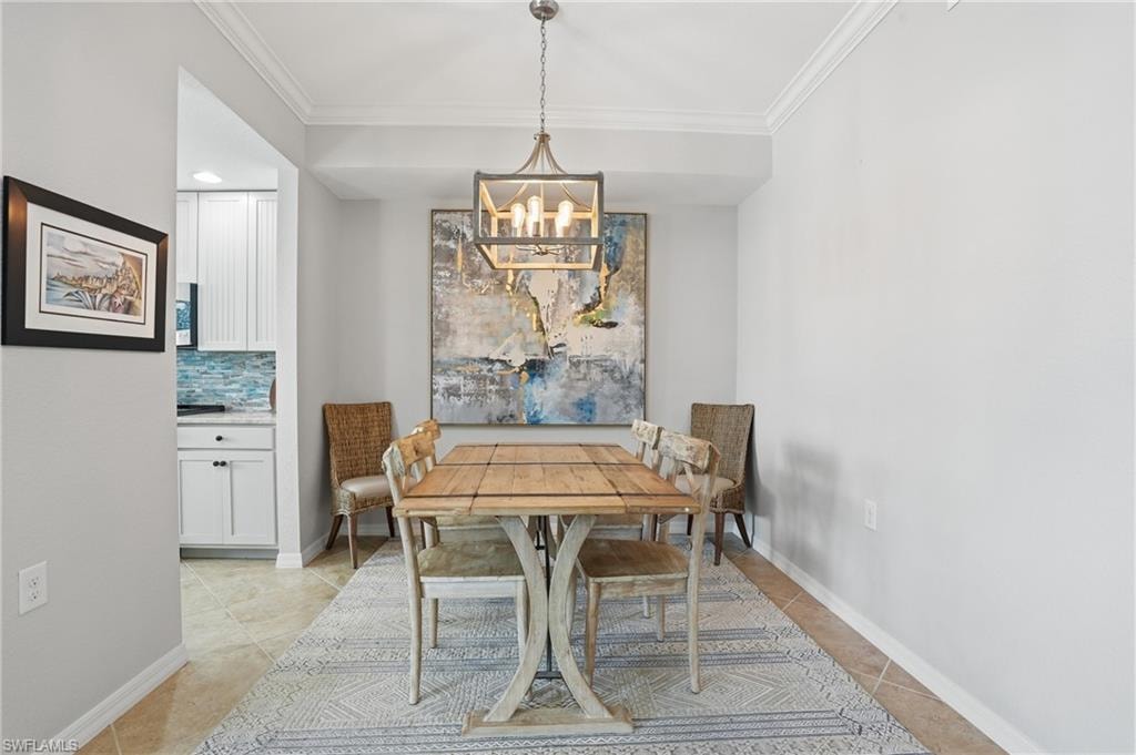 Dining space with crown molding, hanging lights, and light tile patterned floors