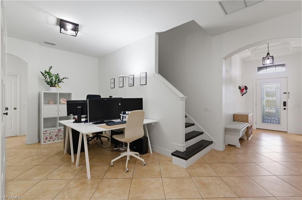 Home office with arched walkways and light tile patterned flooring