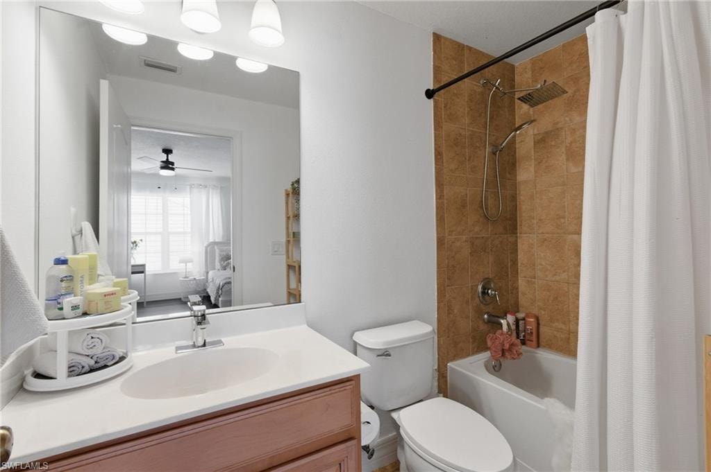 Full bath featuring shower / bathtub combination with curtain, vanity, ensuite bath, and a ceiling fan