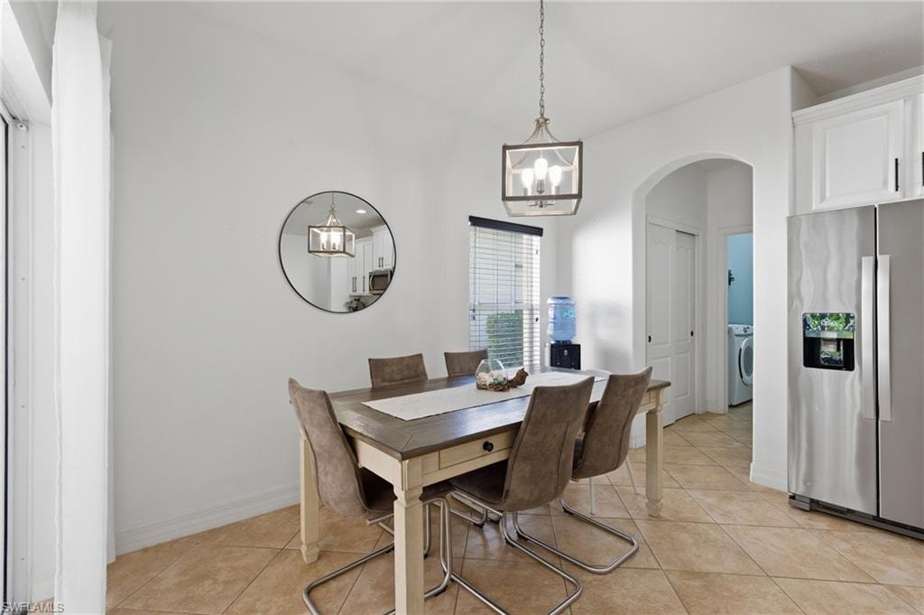 Dining room with arched walkways, hanging lights, light tile patterned flooring, and washer / clothes dryer