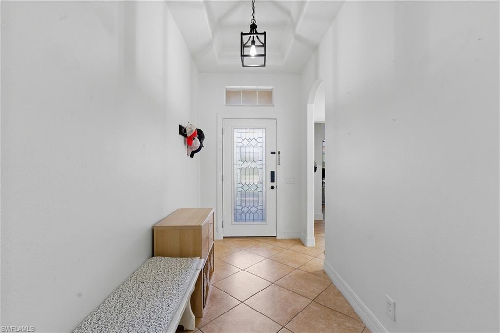 Entryway featuring arched walkways, tile patterned floors, and a tray ceiling