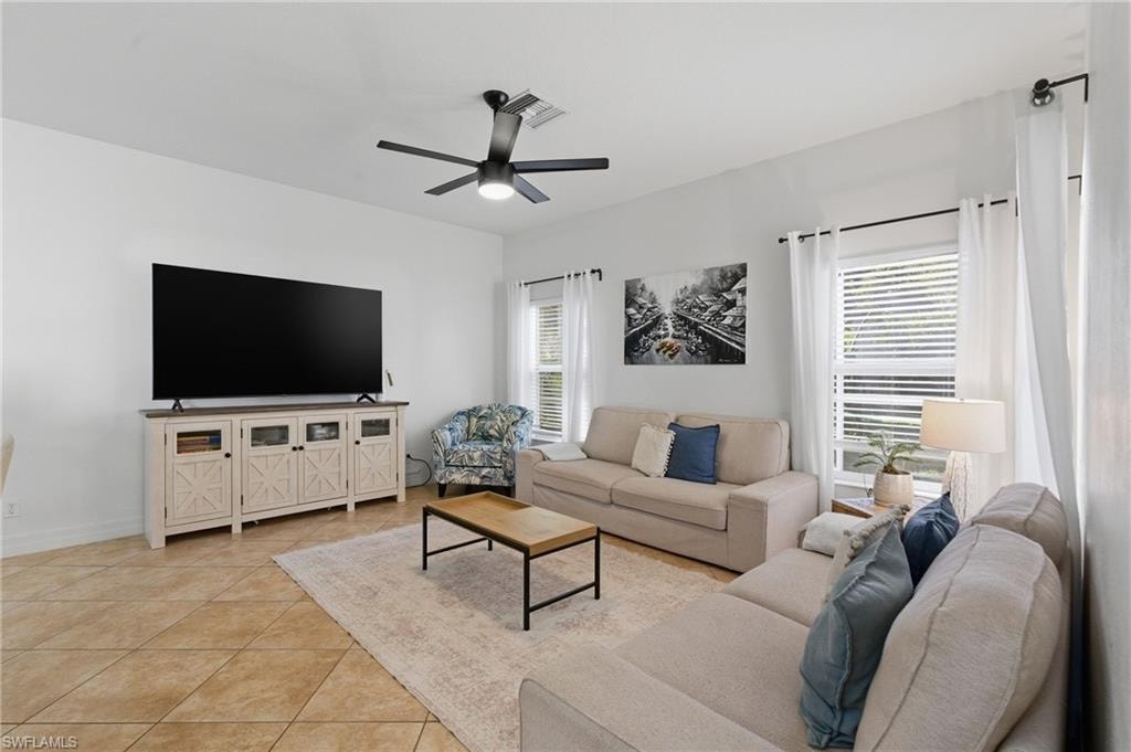 Living area featuring light tile patterned floors, plenty of natural light, and a ceiling fan
