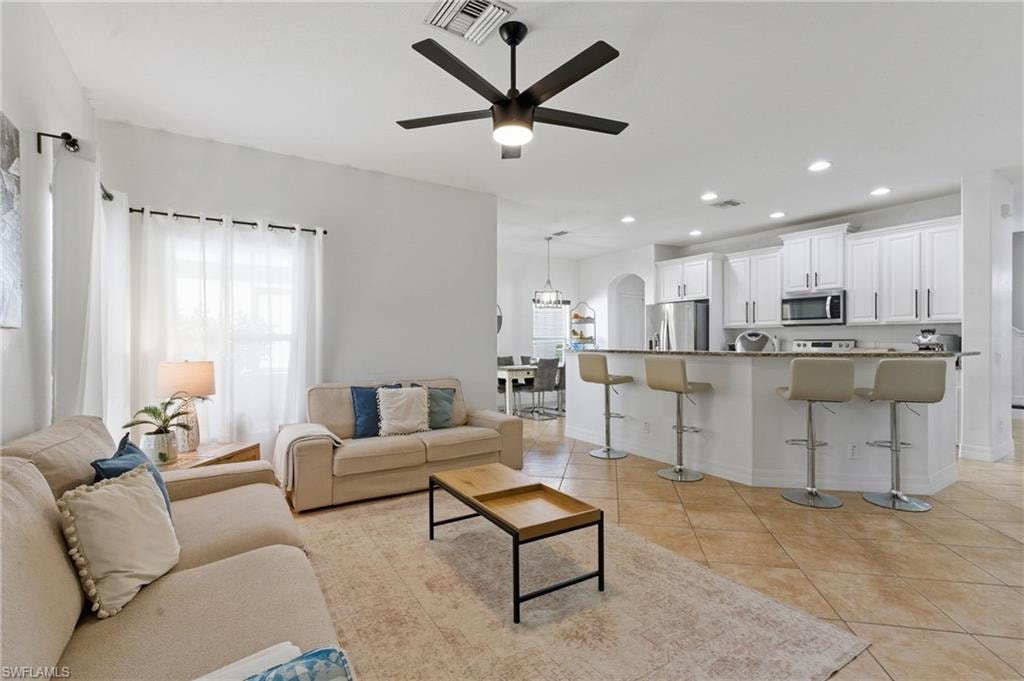 Living room featuring a ceiling fan, recessed lighting, arched walkways, and light tile patterned flooring