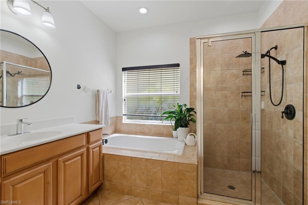 Bathroom featuring a shower stall, a bath, vanity, light tile patterned floors, and recessed lighting