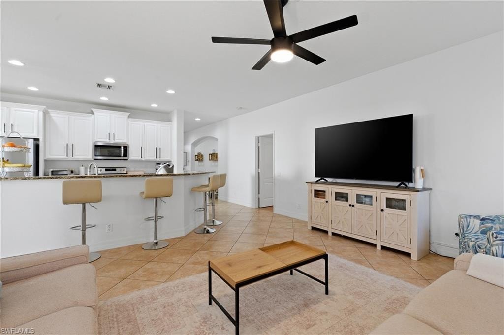 Living room featuring a ceiling fan, arched walkways, recessed lighting, and light tile patterned floors