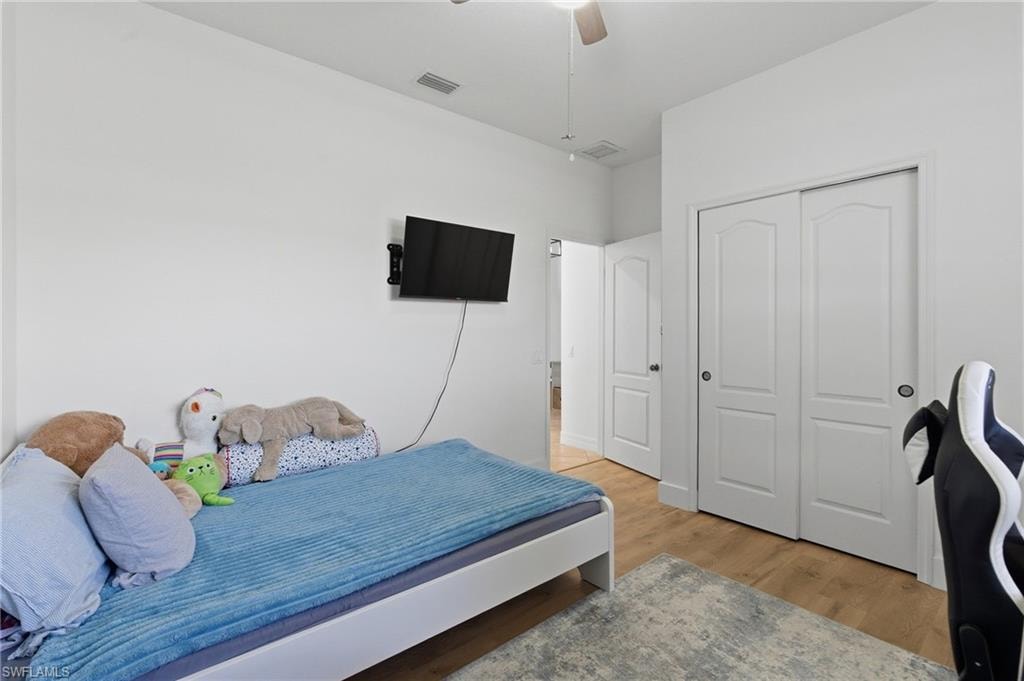 Bedroom featuring light wood finished floors, a closet, and a ceiling fan