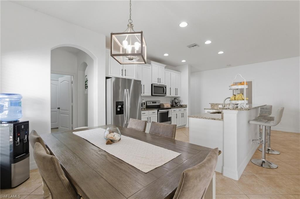 Dining room featuring arched walkways, light tile patterned floors, and suspended lighting