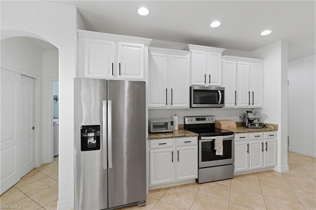 Kitchen featuring stainless steel appliances, light stone counters, white cabinetry, light tile patterned floors, and recessed lighting