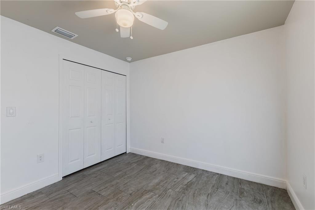 Unfurnished bedroom featuring a closet, wood finished floors, and ceiling fan