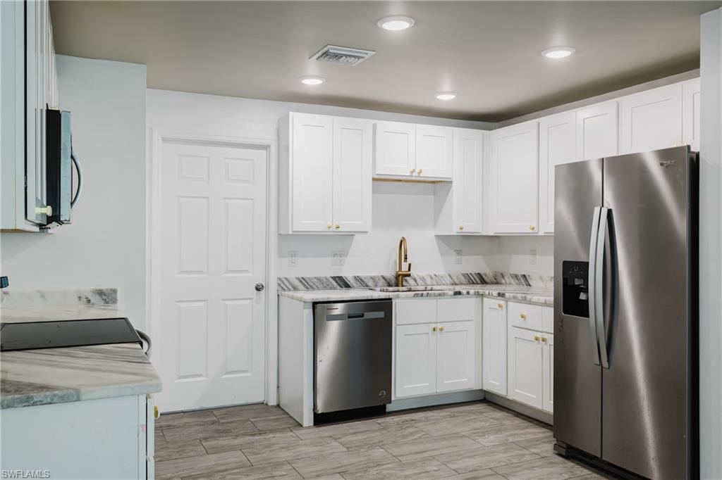 Kitchen featuring stainless steel appliances, white cabinets, wood tiled floors, and recessed lighting