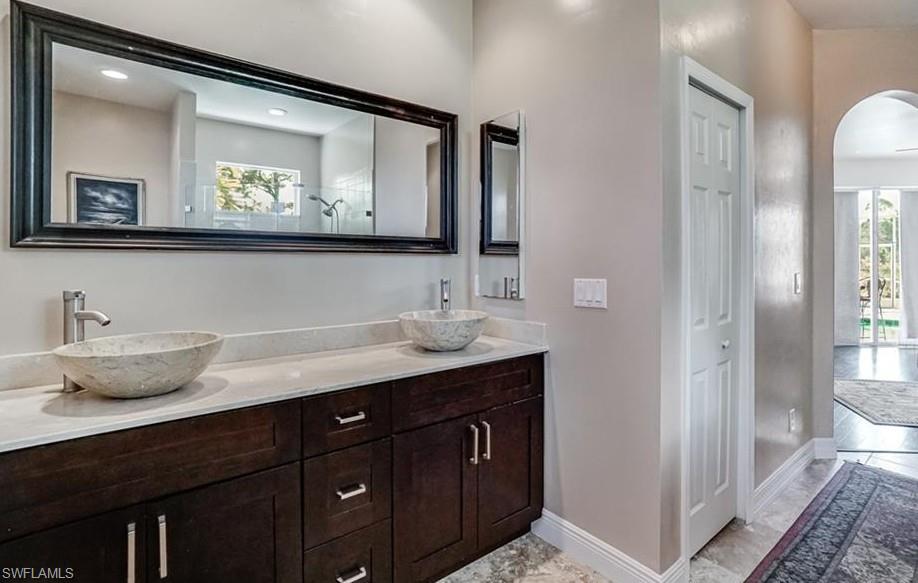 Bathroom with double vanity, a closet, and healthy amount of natural light