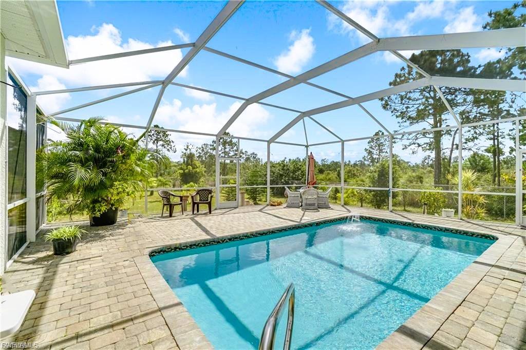 Outdoor pool featuring a sunroom, glass enclosure, and a patio area