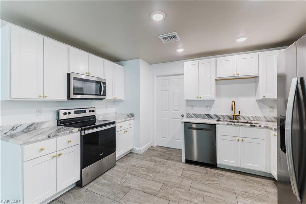 Kitchen featuring stainless steel appliances, white cabinetry, recessed lighting, light stone counters, and wood tiled floors