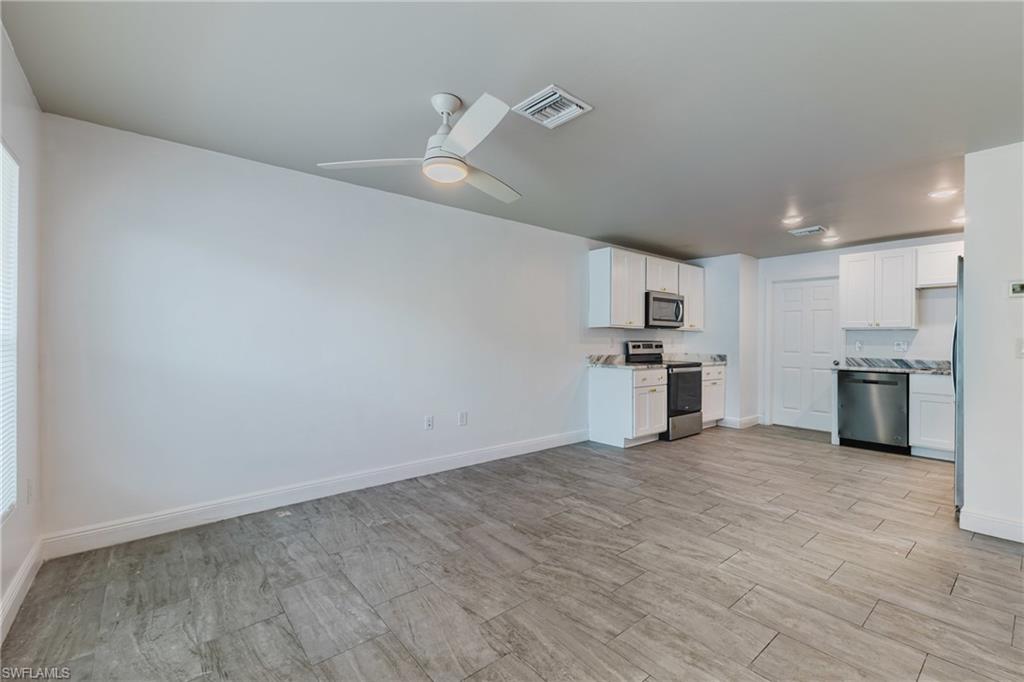Kitchen featuring white cabinets, stainless steel appliances, light countertops, and ceiling fan