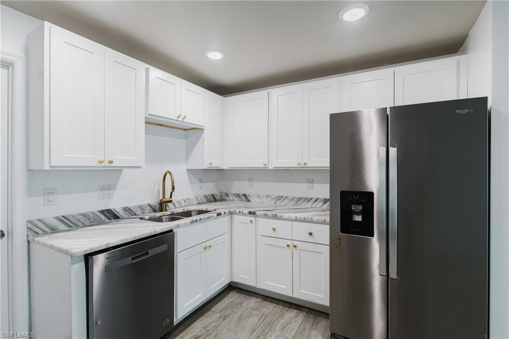 Kitchen with stainless steel appliances, light countertops, white cabinets, and recessed lighting
