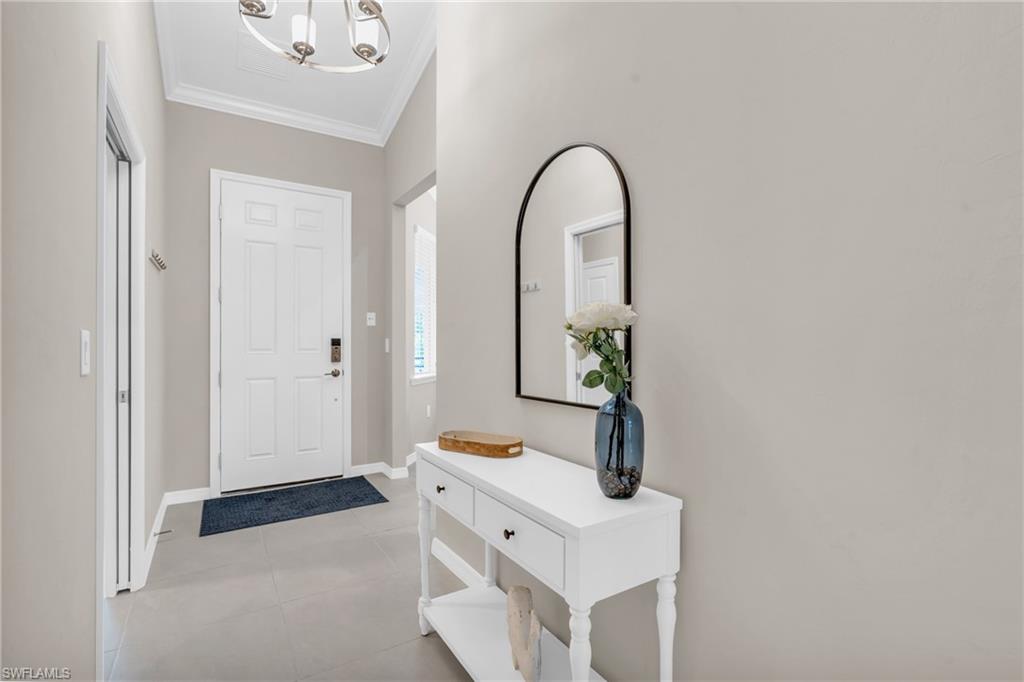 Tiled foyer entrance with a chandelier and crown molding