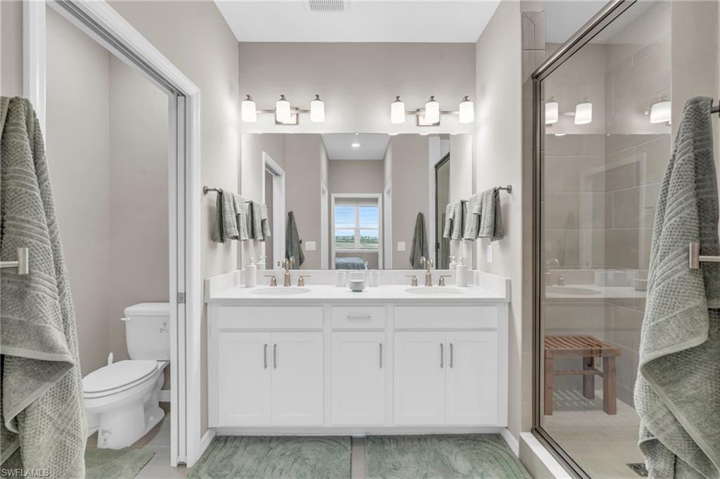 Bathroom with vanity, toilet, and a shower with door