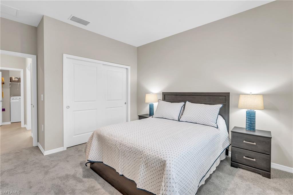Bedroom featuring a closet, light colored carpet, and washer / clothes dryer