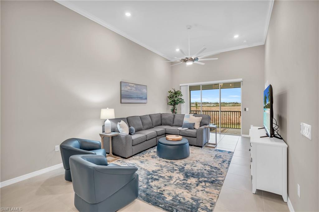 Living room with ceiling fan, crown molding, a towering ceiling, and light tile patterned flooring
