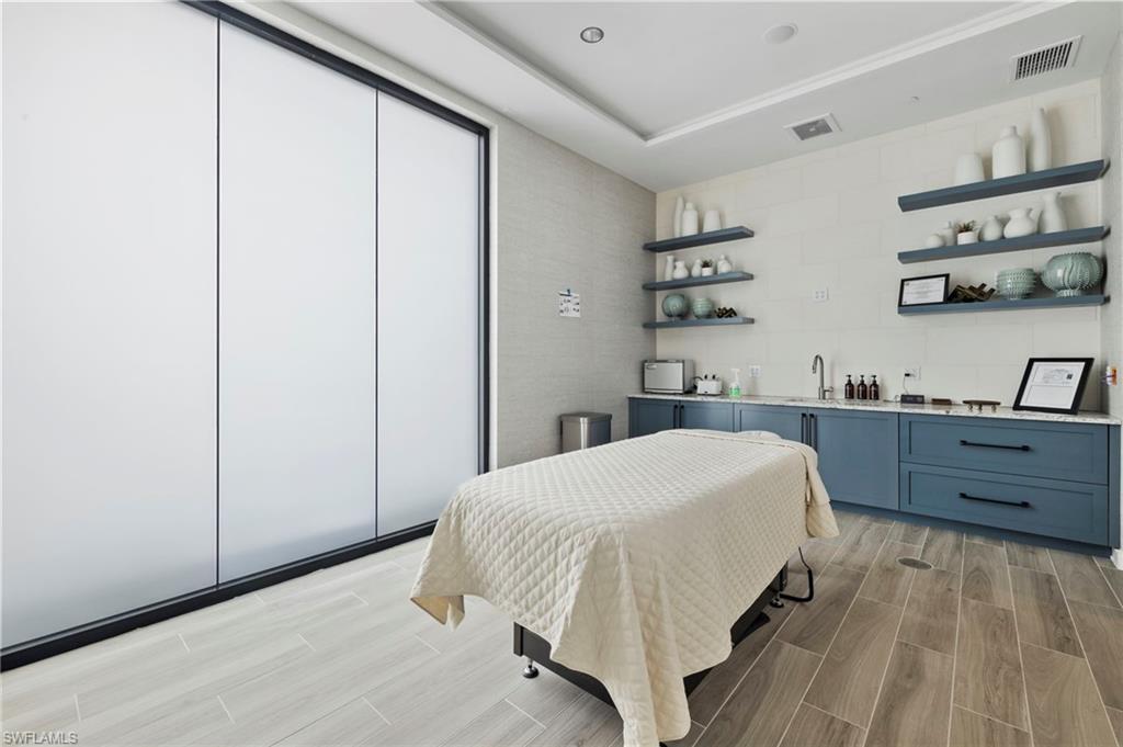 Bedroom with wood tiled floors, tile walls, a raised ceiling, wet bar, and a closet