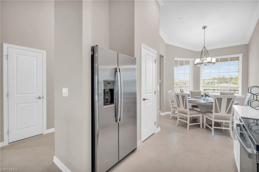 Kitchen with pendant lighting, appliances with stainless steel finishes, lofted ceiling, an inviting chandelier, and light tile patterned floors