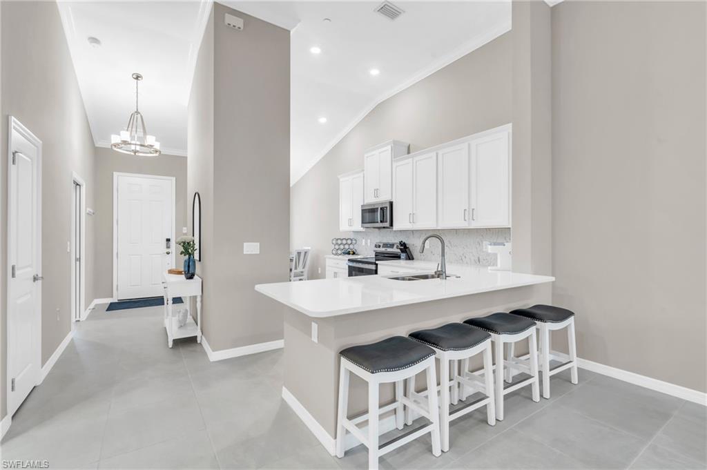 Kitchen with kitchen peninsula, appliances with stainless steel finishes, white cabinetry, and sink