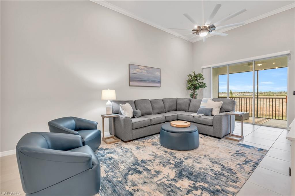 Tiled living room featuring ceiling fan and crown molding