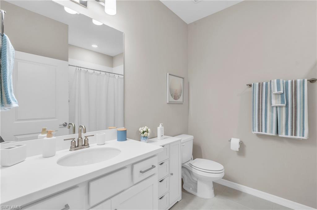 Bathroom with toilet, vanity, a shower with curtain, and tile patterned floors