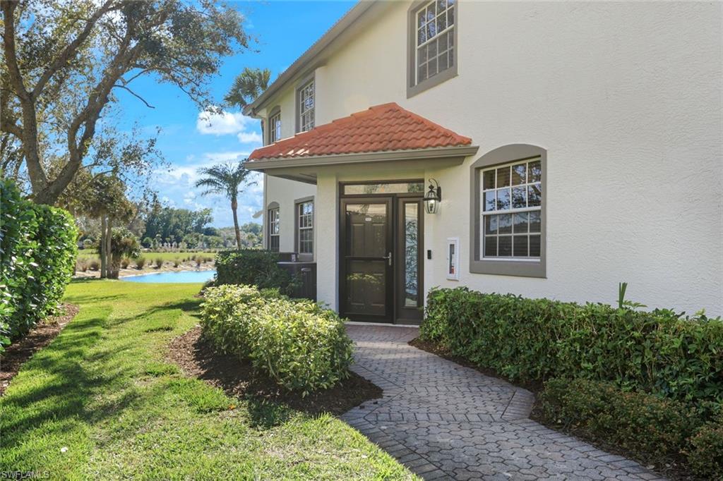 Doorway to property with a yard, stucco siding, and a tile roof