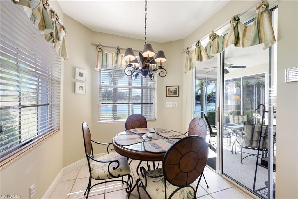 Tiled dining room with ceiling fan, hanging lights, and plenty of natural light