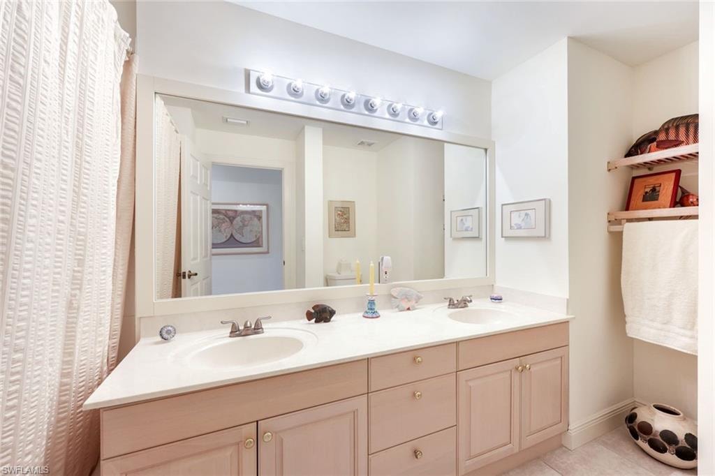 Full bathroom with double vanity, light tile patterned flooring, and curtained shower