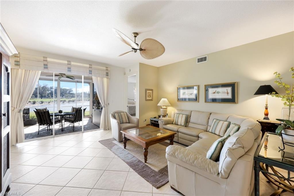Living room with ceiling fan, a water view, and light tile patterned floors